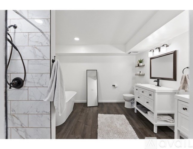 A white bathroom with a marble shower and a white toilet.