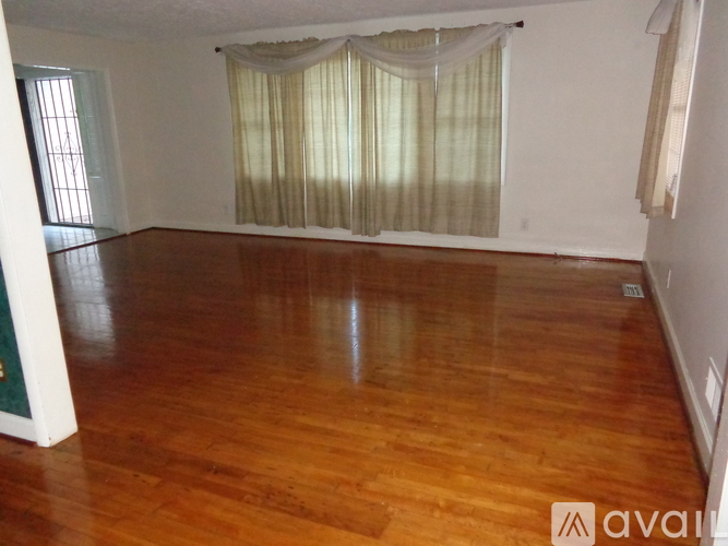 A room with wooden floors and a window with curtains.