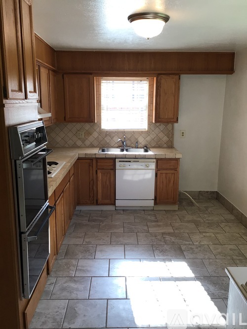 A kitchen with tile flooring and wooden cabinets.