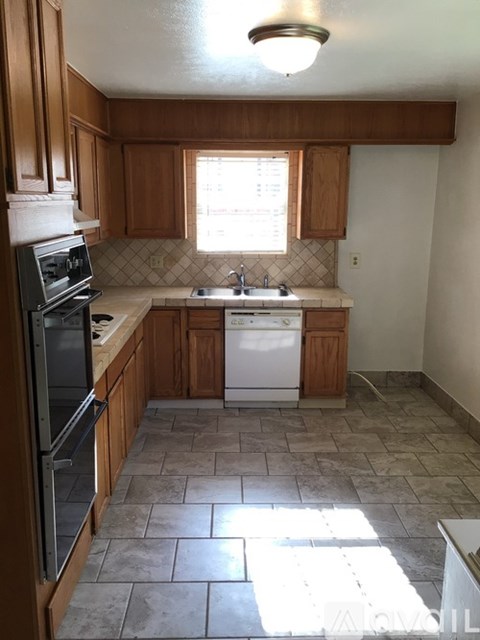 A kitchen with tile flooring and wooden cabinets.