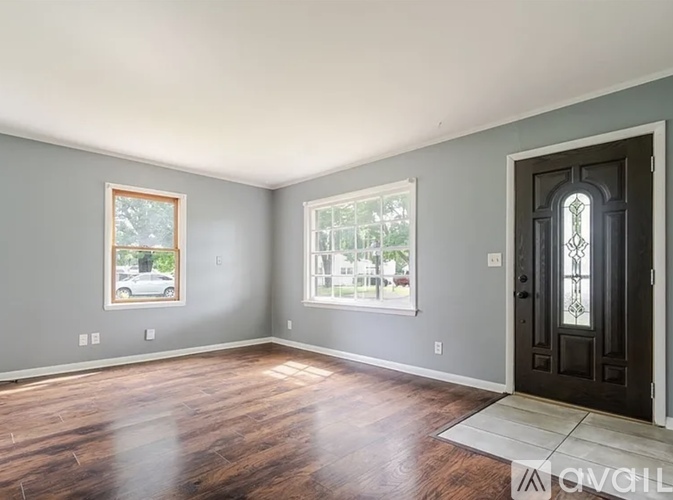 A room with a wooden floor and a black door.