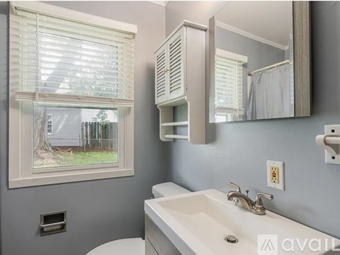 A bathroom with a white sink and a window with blinds.