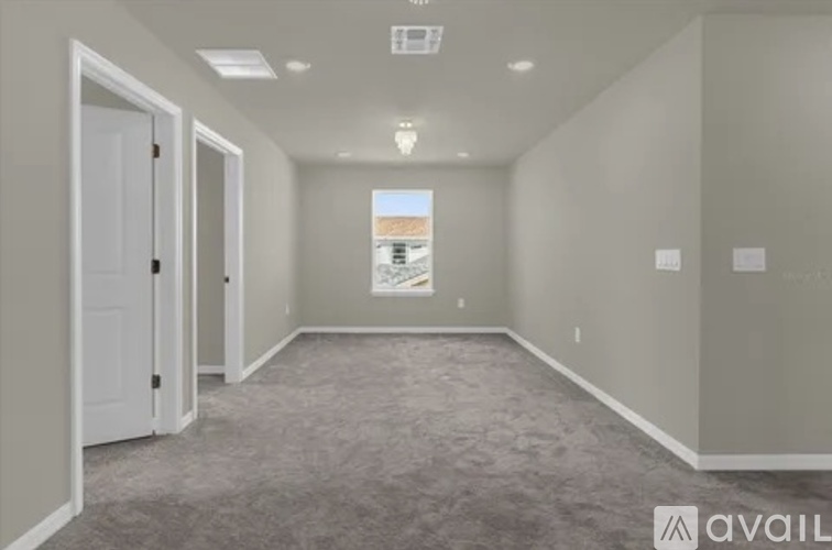 A room with a carpeted floor and a window showing a building outside.