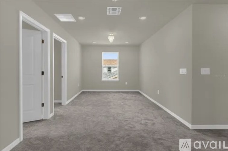 A room with a carpeted floor and a window showing a building outside.