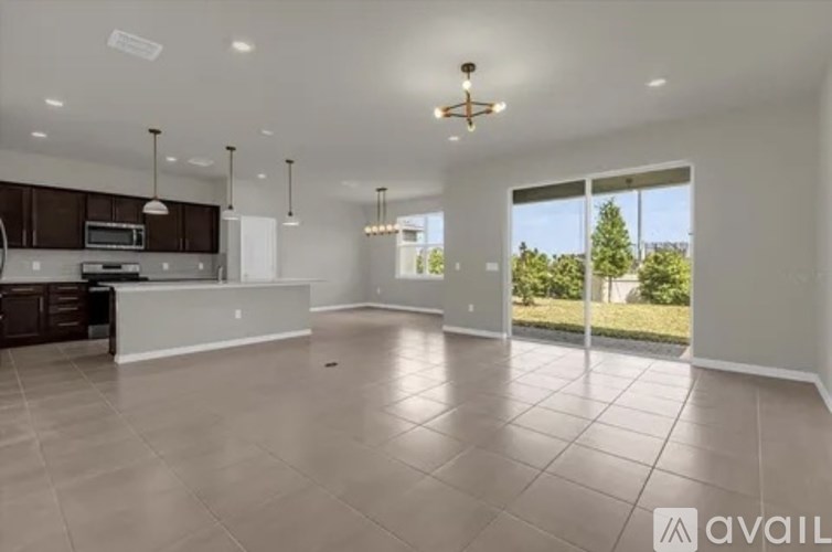 A spacious living room with a kitchen area in the background.