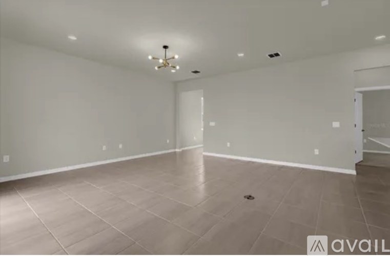 A spacious room with a tiled floor and a chandelier hanging from the ceiling.