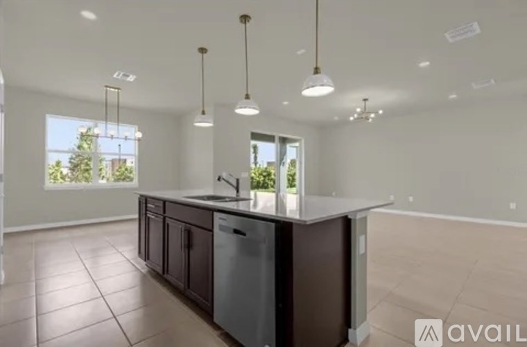 A kitchen with a large island and pendant lights.