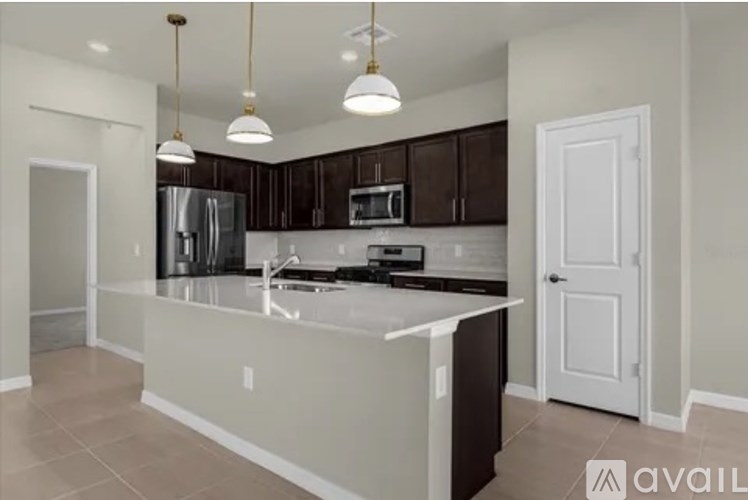 A kitchen with a white countertop and dark brown cabinets.