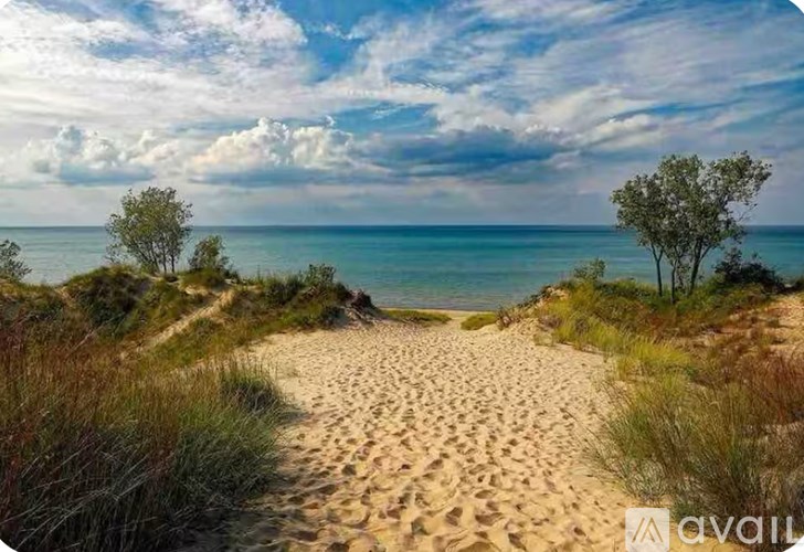 A path through a sandy beach leading to a body of water.