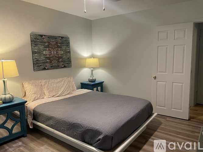 A bedroom with a bed, two lamps, and a painting on the wall.