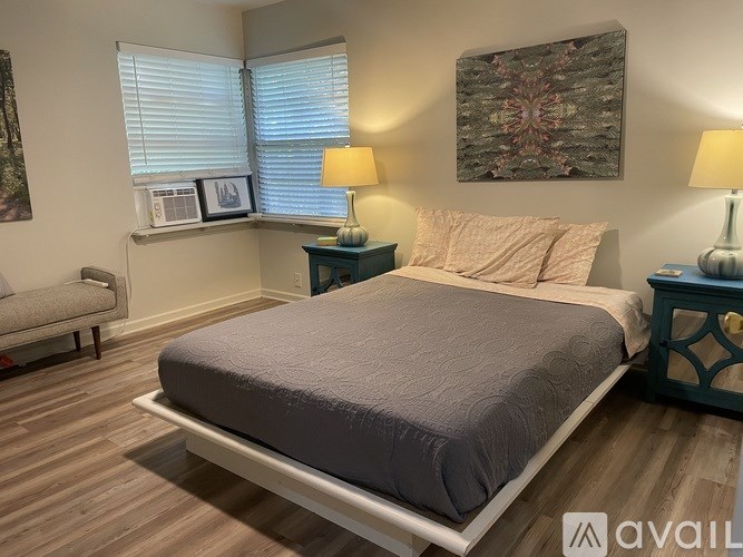 A bedroom with a bed, nightstands, and a window.