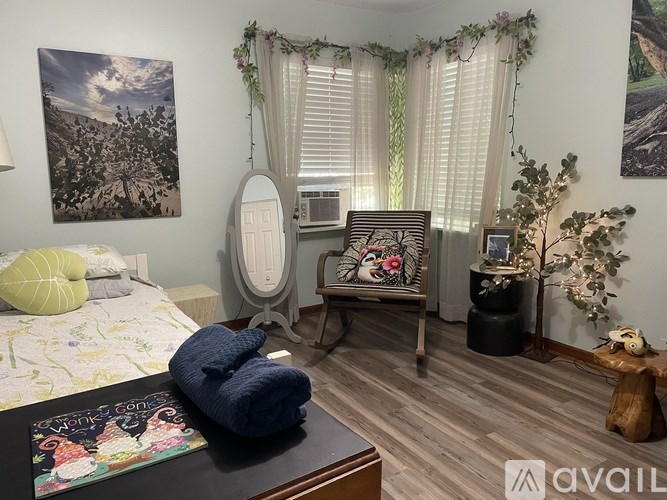 A cozy bedroom with a bed, chair, and decorations.