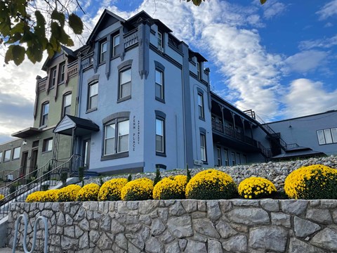 A building with a stone wall and yellow flowers in front.