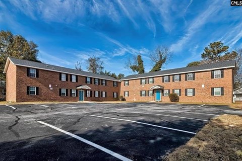 A large parking lot in front of a brick building.