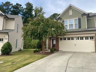 A two-story house with a garage is surrounded by a well-maintained lawn.