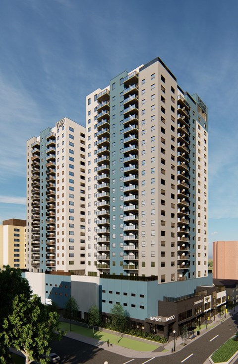 A modern multi-story building with a glass facade stands tall against a clear sky.