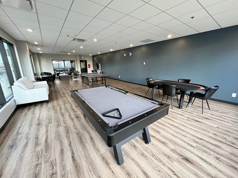 A billiard table is in the middle of a room with a pool table and a ping pong table.