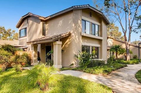 A modern house with a beige exterior and a well-manicured lawn.