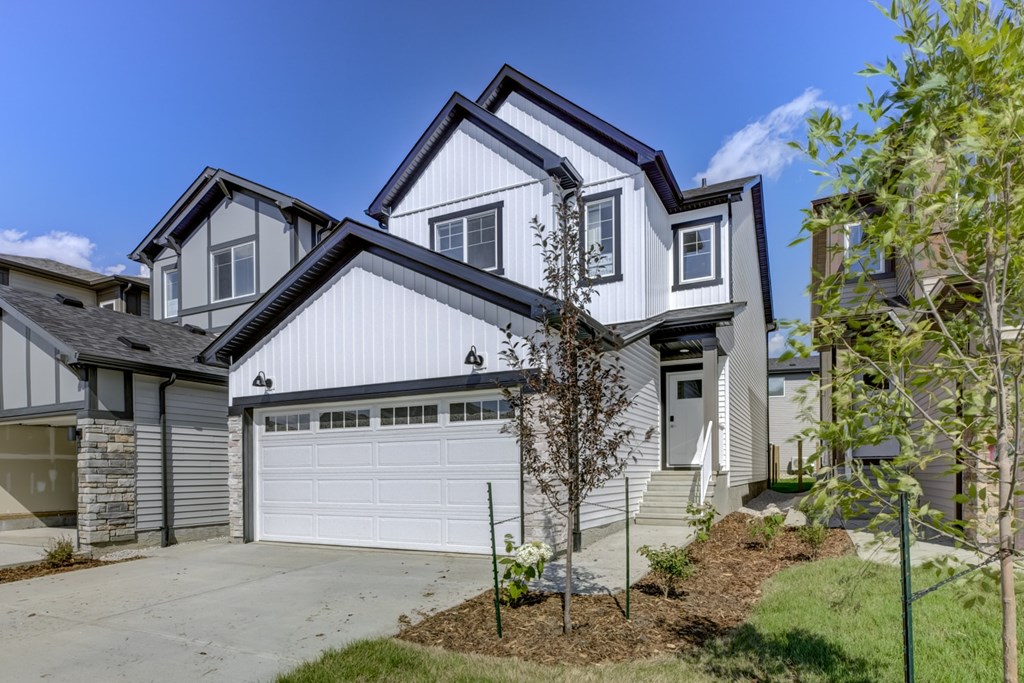 A modern house with a white garage door and a grey roof.