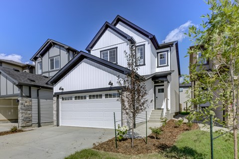A modern house with a white garage door and a grey roof.