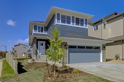 A modern house with a grey garage door and a white door.