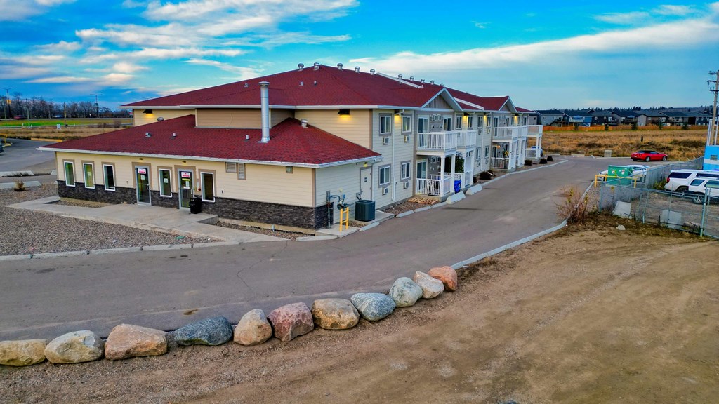 A building with a red roof and a parking lot in front.