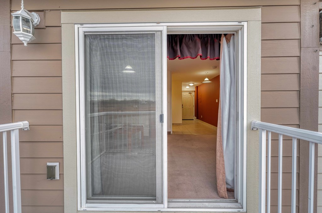 A glass door with a curtain is open to a room.