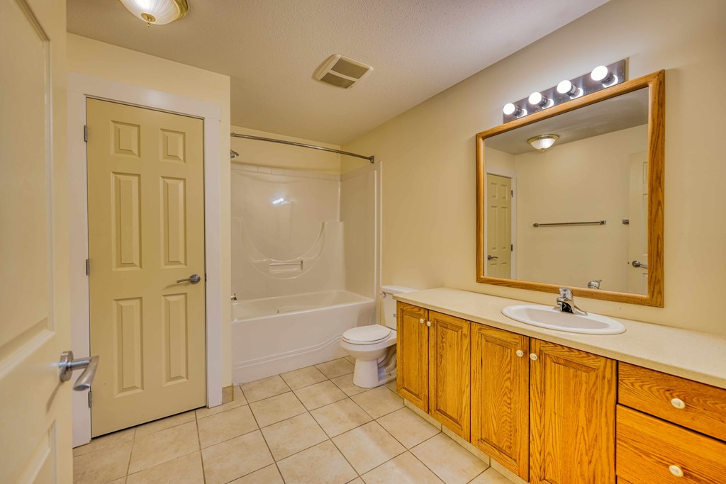 A bathroom with a toilet, sink, and mirror.