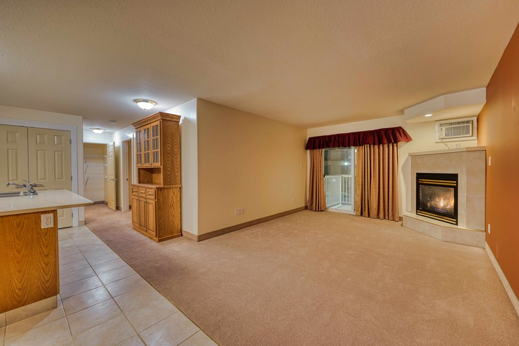 A living room with a fireplace and a kitchen area.