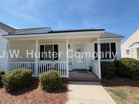 A white house with a porch and a sign that says J.W. Hunter Company.