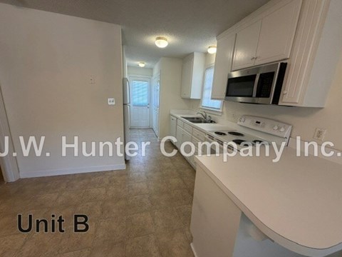 A kitchen with white cabinets and appliances in a unit labeled B.