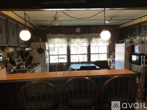 A kitchen with wooden chairs and a sign that says "And I'm a great cook".