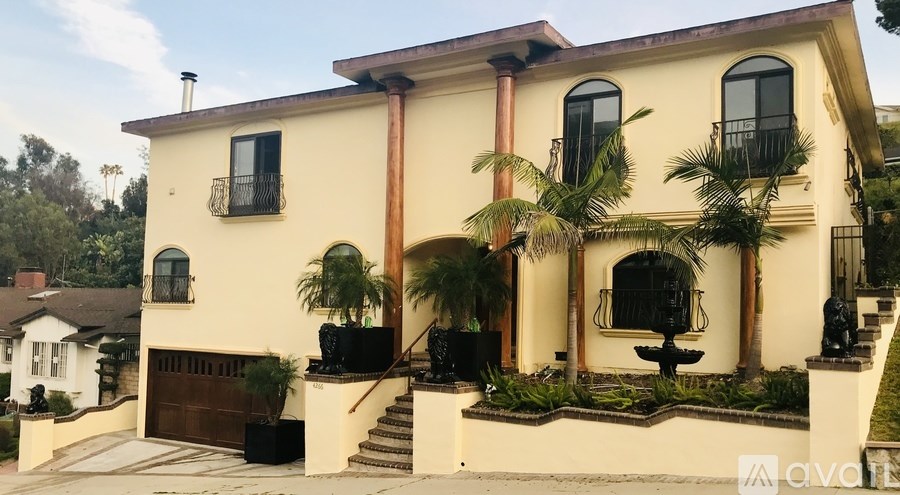 A yellow house with a black gate and a small garden in front.