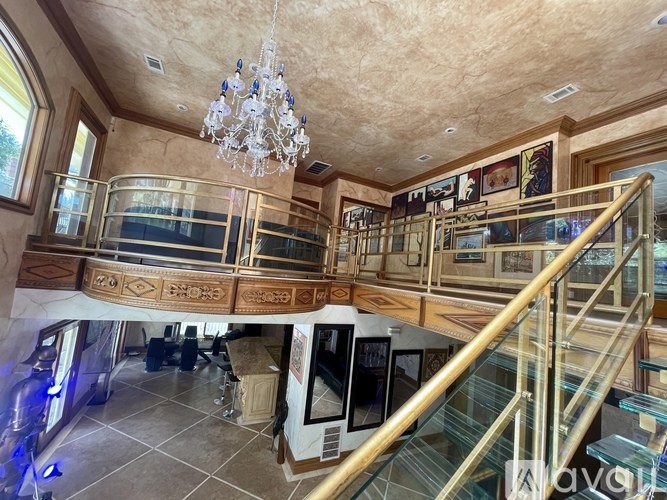 A grand staircase with a glass railing and a chandelier hanging from the ceiling.