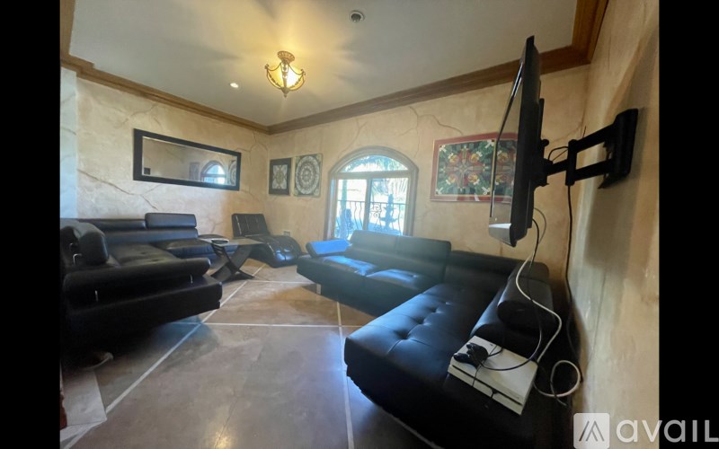 A living room with a black couch and a television mounted on the wall.