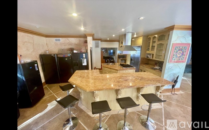 A kitchen with a marble island and bar stools.