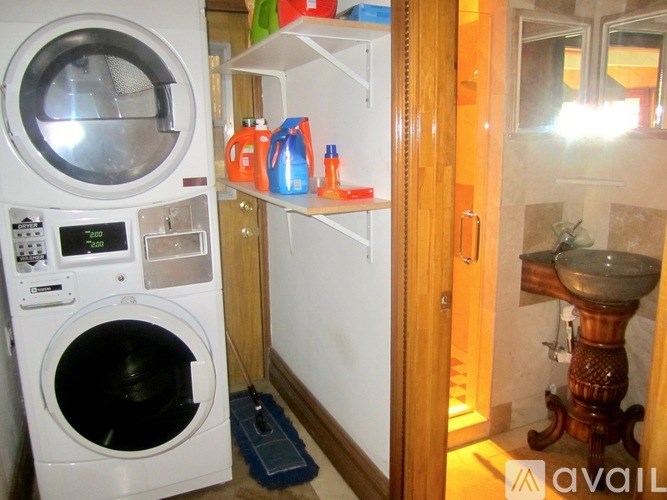 A small laundry room with a washer and dryer, a sink, and a mirror.