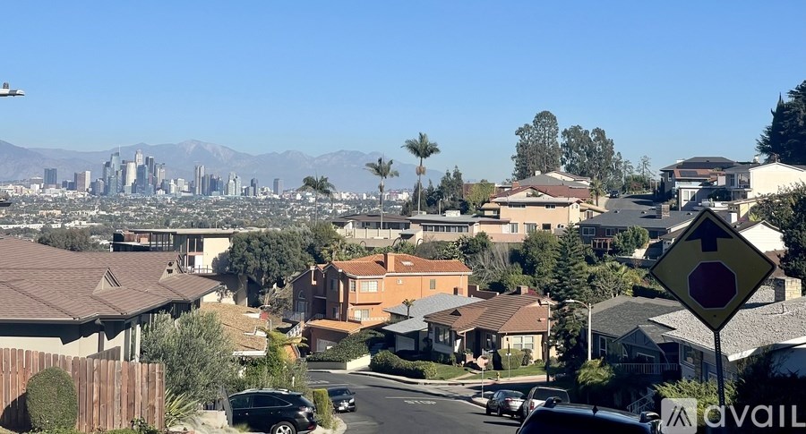 A residential street with a stop sign and a view of the city in the distance.