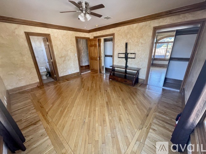 A room with wooden flooring and a ceiling fan.
