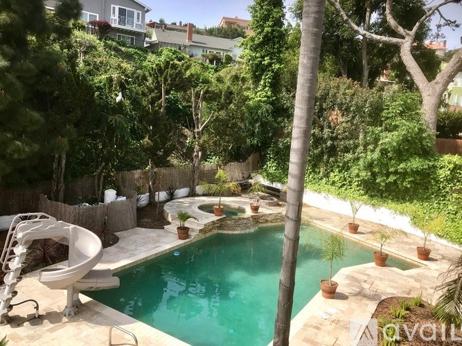 A pool surrounded by a garden and trees.