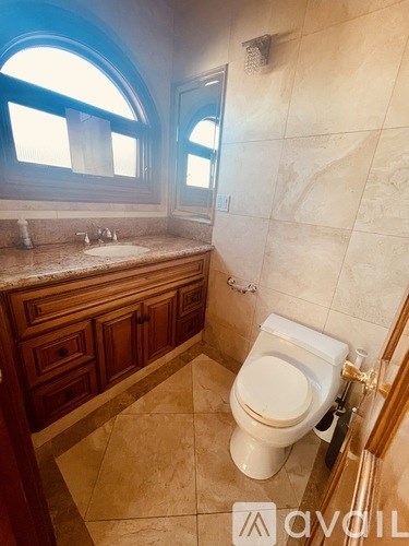 A bathroom with a toilet, sink, and a window.
