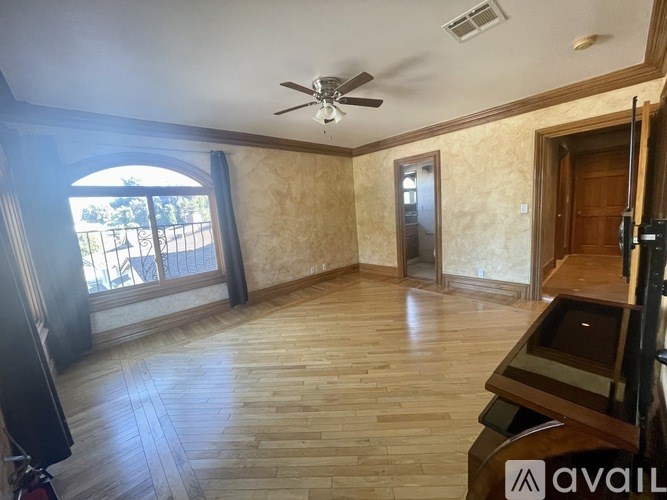 A room with wooden flooring and a ceiling fan.
