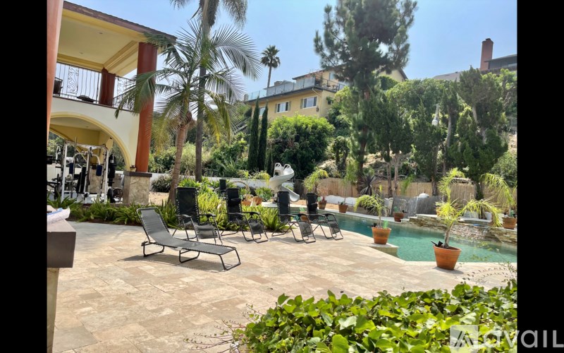 A patio with chairs and a pool in the background.