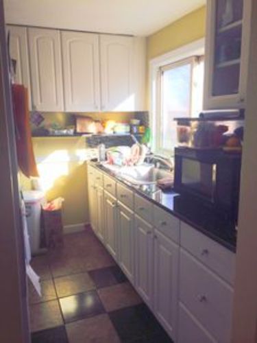A kitchen with white cabinets and a black and white checkered floor.