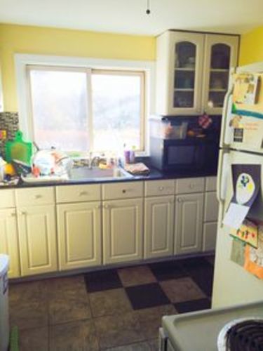 A kitchen with a checkered floor and a refrigerator on the right.
