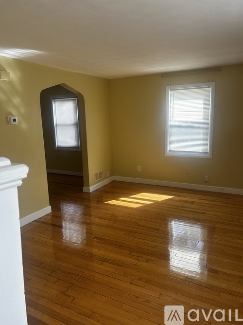 A room with wooden floors and a window with blinds.