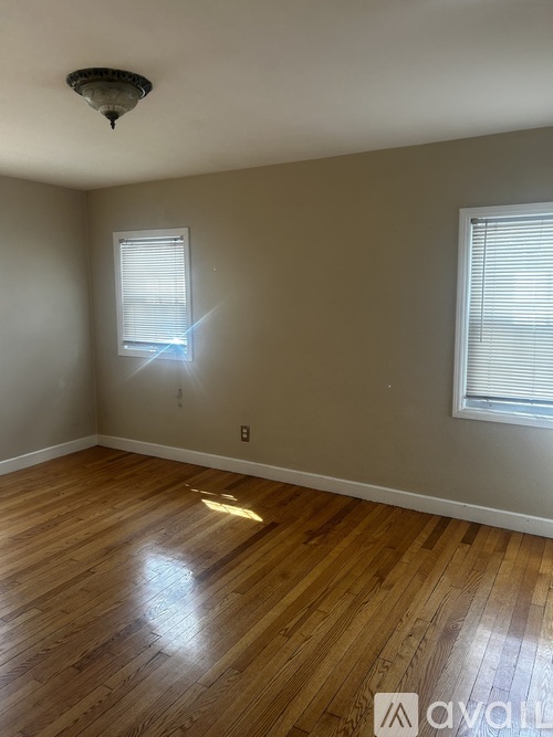 A room with wooden floors and two windows.