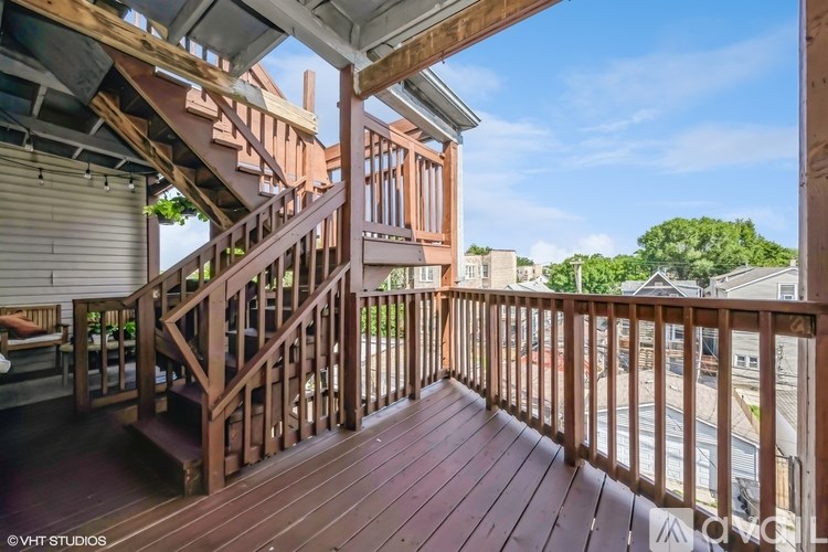 A wooden deck with a staircase leading to a balcony.