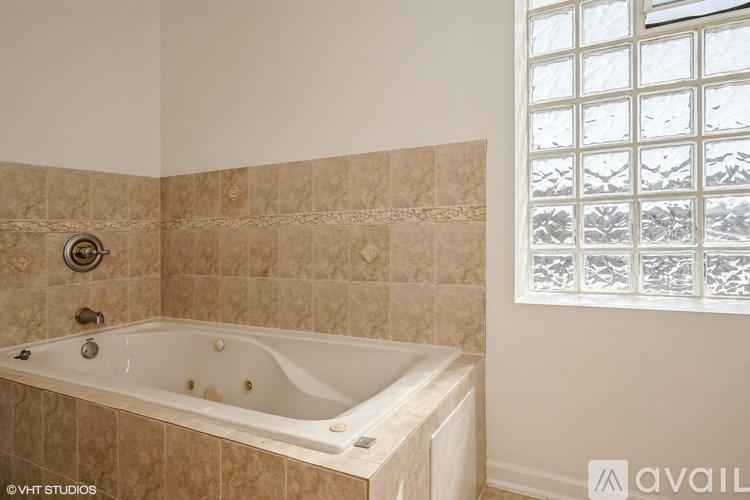 A bathroom with a tiled wall and a bathtub.