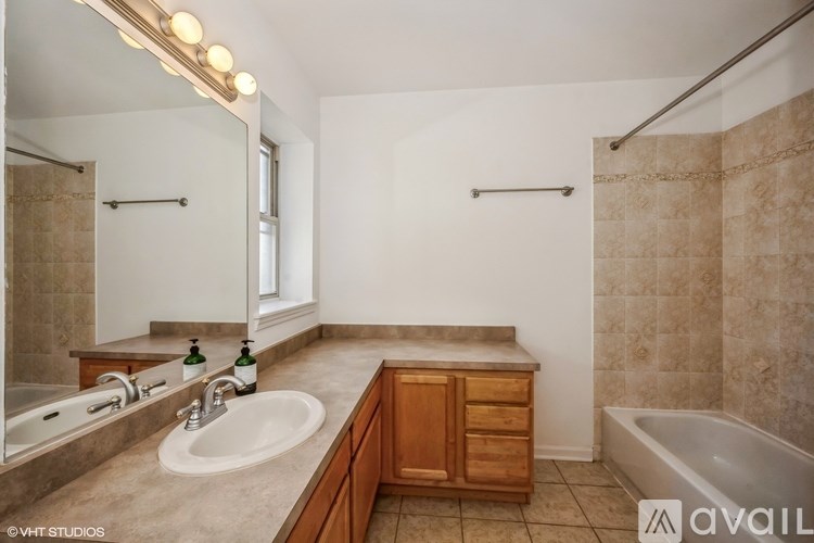 A bathroom with a tub, sink, and mirror.